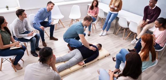 First aid training UK with First Response. Group of learners practicing.